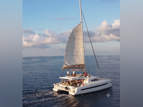 A catamaran sails gracefully through calm waters, with guests enjoying the experience on deck — perfect for sailing adventures and scenic tours.