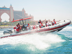A lively group enjoys an exhilarating ride on a speedboat, showcasing the excitement of water activities against a stunning backdrop of the Atlantis hotel.