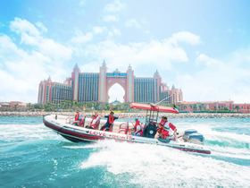 A lively group enjoys a thrilling ride on a speedboat near the iconic Atlantis resort, showcasing the excitement of water activities in a stunning setting.