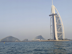 A stunning view of the iconic Burj Al Arab and modern architecture along the Dubai coastline, showcasing the city's unique skyline and vibrant atmosphere.