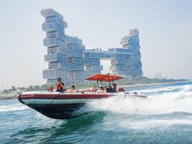 A lively group enjoys an exhilarating ride on a speedboat, with a stunning modern cityscape in the background — perfect for adventure seekers exploring the coastline.