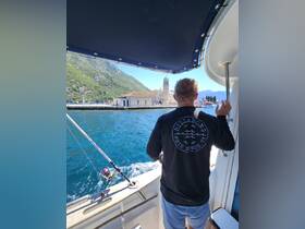 A person enjoys a scenic view while fishing from a boat, with a picturesque island and church in the background — a perfect moment for adventure seekers on the water.