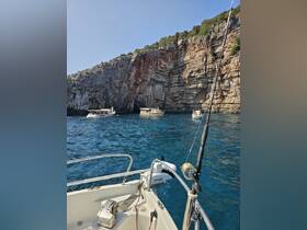 A scenic view of multiple boats anchored near a stunning rocky coastline, showcasing the beauty of a popular boating destination.