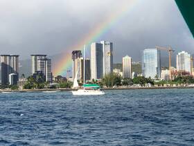 A picturesque view of a sailboat sailing past a vibrant city skyline under a rainbow, capturing the beauty of urban life and nature in harmony.