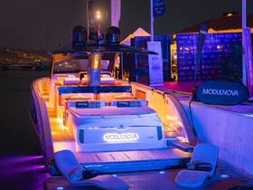 A beautifully lit interior of a MODULNOVA TT420 boat, showcasing luxurious seating and lounge areas, perfect for evening gatherings and events on the water.