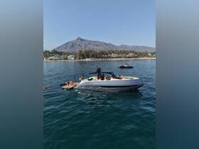 A lively scene featuring a group enjoying a day on the water, with a stylish boat anchored near the shore and picturesque mountains in the background.
