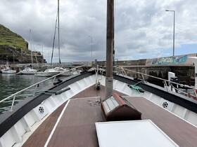 A scenic view of a yacht docked at a marina, showcasing the vessel's structure and surrounding boats against a cloudy sky.