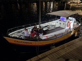 A lively group enjoys an evening gathering aboard the CALCAMAR, featuring a cozy dining setup under the stars — perfect for memorable nights on the water.