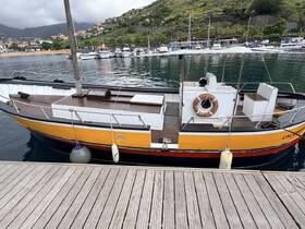 A vibrant view of a docked boat named 'CALAMANDRA,' showcasing its unique design and structure against a scenic harbor backdrop.
