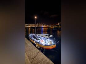 A beautifully illuminated boat named 'CALCAMAR 105117-4PT' docked at night, showcasing the vibrant lights of the harbor in the background.