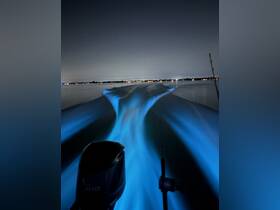 A stunning night view from a boat, showcasing the illuminated wake and distant shoreline lights — perfect for nighttime boating adventures.