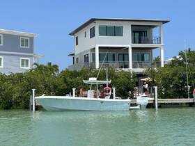 A boat approaches a dock with people visible, set against a backdrop of beautiful waterfront homes — a perfect scene for a day out on the water.