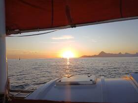 A serene sunset view from the deck of a boat, showcasing the tranquil waters and distant mountains — perfect for capturing the beauty of evening cruises.