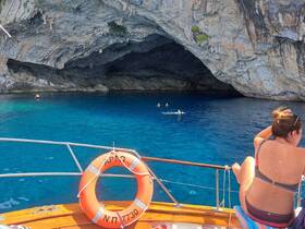 Guests enjoy swimming in the stunning blue waters near a cave, creating a memorable adventure on the boat.
