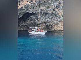 A lively group enjoys a boat tour near a stunning cave, showcasing the beauty of the coastline and the vibrant blue waters.