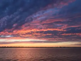 A stunning sunset paints the sky with vibrant colors over calm waters, creating a picturesque scene perfect for evening boat trips or relaxation by the shore.