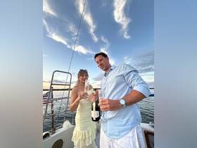 A couple celebrates with champagne on a sailboat at sunset, creating a romantic atmosphere perfect for special occasions on the water.