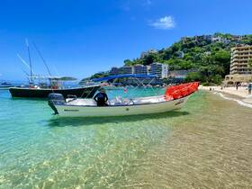 A scenic view of a boat anchored near a sandy beach, with lush hills and buildings in the background, perfect for showcasing coastal adventures.