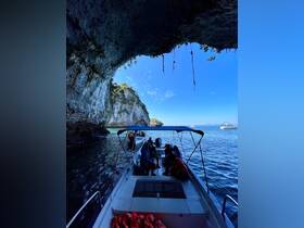 A group of guests aboard a boat explores a stunning cave, surrounded by beautiful rock formations and clear waters — a perfect adventure for nature lovers.