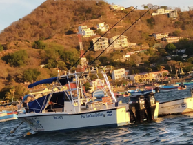 A fishing boat anchored in a picturesque harbor, showcasing its structure against a backdrop of hillside homes — ideal for fishing excursions and coastal tours.