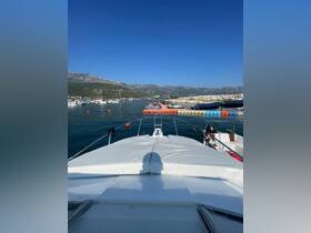 A serene view from the front of a yacht docked in a picturesque marina, surrounded by other boats and stunning mountain scenery.