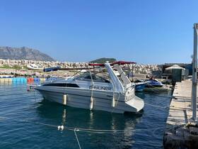 A Bayliner boat docked in a serene marina, surrounded by clear waters and scenic mountains — perfect for a day out on the water.