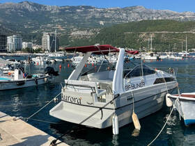 A sleek Bayliner boat docked in a picturesque marina, surrounded by other vessels and scenic mountains in the background.