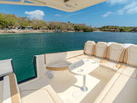 A spacious and stylish interior seating area of a boat, featuring comfortable cushions and a table, perfect for relaxing while enjoying the scenic waterfront views.