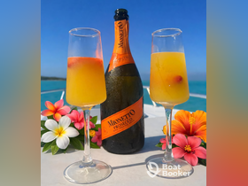 Two refreshing cocktails made with prosecco are beautifully presented with tropical flowers, perfect for enjoying on a sunny day aboard a boat.