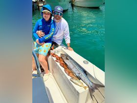 A father and son proudly display their fishing catch aboard a boat, showcasing a successful day on the water. This memorable moment highlights the joy of fishing and family bonding.