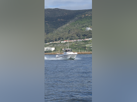 A speedboat named 'Stella Maria' glides through the water, showcasing its sleek design against a scenic backdrop of lush hills.