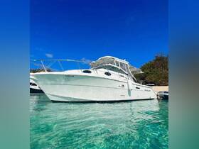 A stunning view of a Wellcraft boat docked in crystal-clear waters, showcasing its sleek design against a vibrant blue sky — perfect for a day on the water.