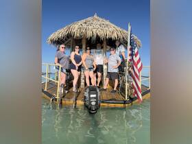 A cheerful group poses together on a tiki boat, enjoying a sunny day on the water — perfect for memorable gatherings and celebrations.