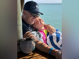 A joyful moment captured between a father and daughter, both smiling and enjoying their time together by the water — perfect for family bonding experiences on a boat.