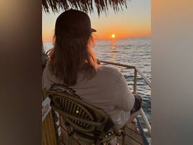 A serene sunset view from a boat, with a person enjoying the tranquil moment — perfect for unwinding on the water.