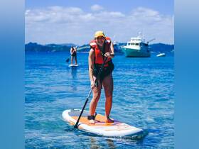 A woman enjoys paddleboarding in crystal-clear waters, showcasing the fun and adventure of water sports during a sunny day.