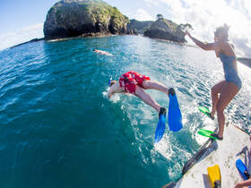 Exciting snorkeling adventure as two friends leap into the crystal-clear ocean, ready to explore the underwater world. Perfect for thrill-seekers and marine enthusiasts.