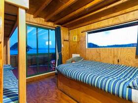 Interior view of a cozy boat cabin featuring two beds and large windows showcasing scenic views — perfect for relaxing during your nautical adventures.