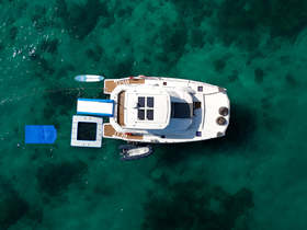 Aerial view of a sleek yacht anchored in crystal-clear waters, showcasing its elegant design and onboard amenities.