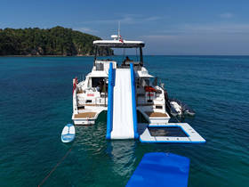 A luxurious boat equipped with a water slide and floating mat, perfect for fun-filled days on the water. Enjoy paddleboarding in the clear turquoise waters while soaking up the sun.