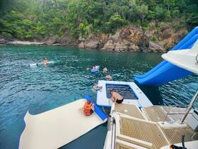 A lively group enjoys a fun day on the water, featuring swimming, a water slide, and a floating mat — perfect for summer adventures and family outings.