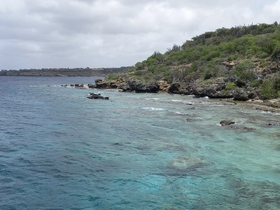 A stunning view of a rocky coastline with clear turquoise waters, showcasing the natural beauty of the island — perfect for eco tours and scenic boat trips.