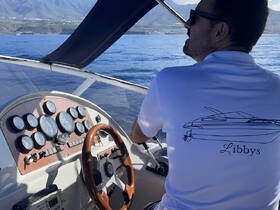 A close-up view of the helm and console of a boat, with a captain at the wheel, showcasing the intricate controls and gauges essential for navigation.