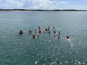 A lively group enjoys a refreshing swim in clear waters, celebrating their day on the water with smiles and excitement.