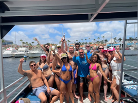 A lively group celebrates aboard a boat, enjoying drinks and sunshine — perfect for a fun day out on the water with friends.