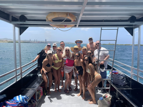 A lively group of friends poses for a fun photo aboard a boat, capturing the joy of their celebration on the water.