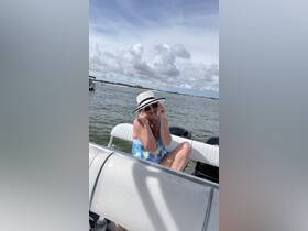 A woman enjoys a sunny day on the water, playfully adjusting her sunglasses while relaxing on a boat — a perfect moment for summer fun and adventure.