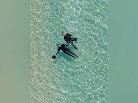 A couple enjoys a refreshing swim in crystal-clear waters, showcasing the beauty of aquatic adventures.