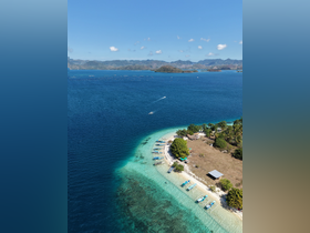 A stunning aerial view of a serene island coastline with turquoise waters and anchored boats, perfect for showcasing the beauty of tropical destinations.
