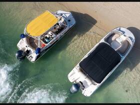 Aerial view of two speedboats docked on a sandy beach, showcasing their sleek designs and inviting atmosphere for water adventures.